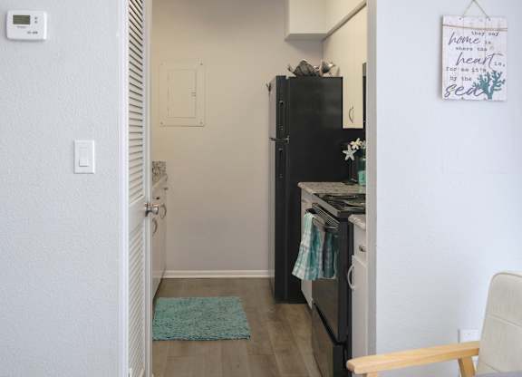 a galley kitchen with black appliances and wood-style flooring