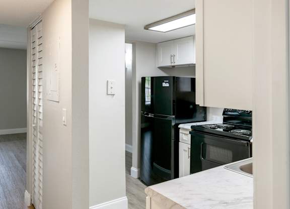 a kitchen with black appliances and white cabinets in a Ridge Apartment home