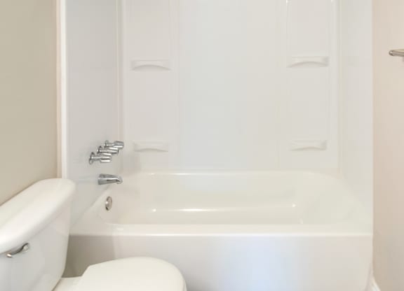 a toilet and shower and tub with shelves for soap and shampoo