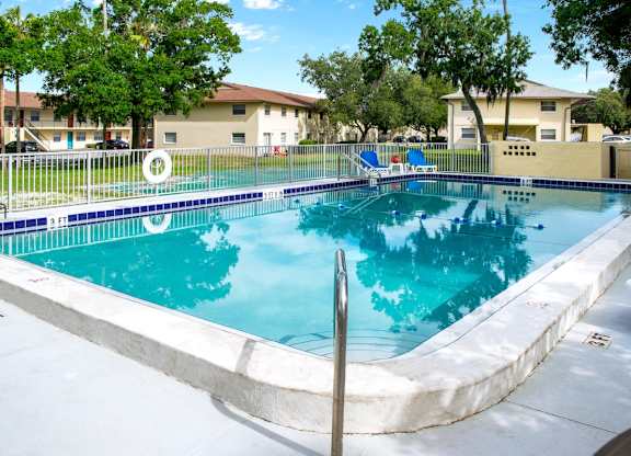 a blue swimming pool and a sundeck with loungers at Ridge Apartments
