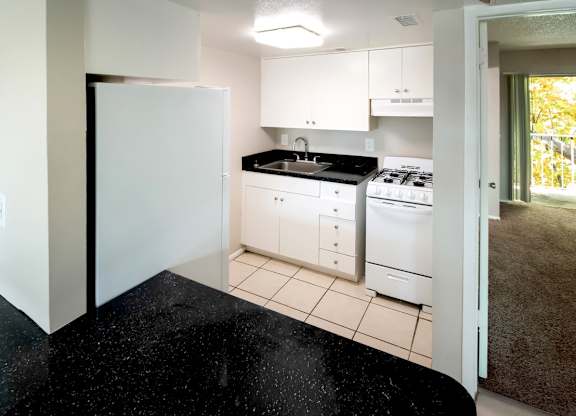 a kitchen with white appliances and black counter tops