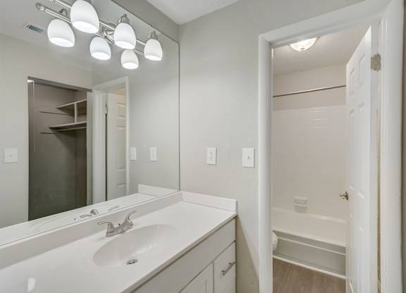 a bathroom with a mirror, vanity, and tub and shower at Hills at Hoover 35216