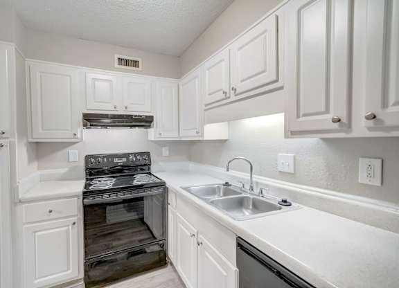 a kitchen with black appliances and white cabinets at Hills at Hoover 35216