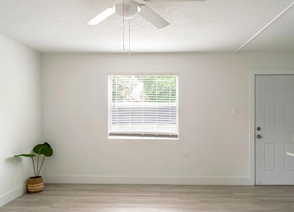 an spacious living room with a window and an illuminated ceiling fan