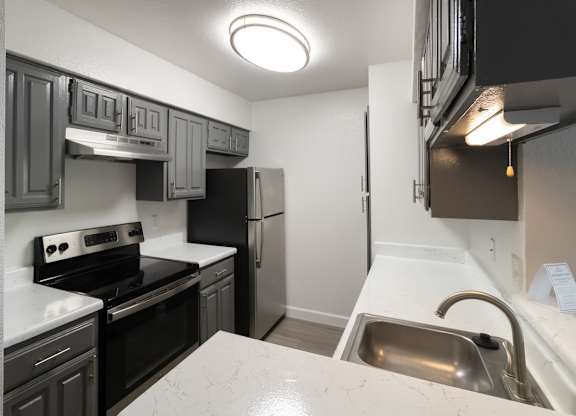 A renovated kitchen with upgraded appliances, dark cabinets, and light countertops