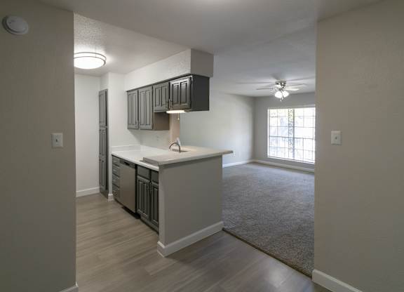 a spacious kitchen with stainless steel appliances and living room with a ceiling fan