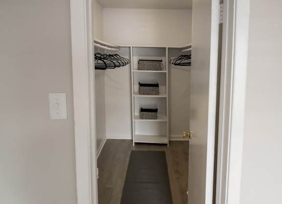 a walk in closet with shelves and hanging bars