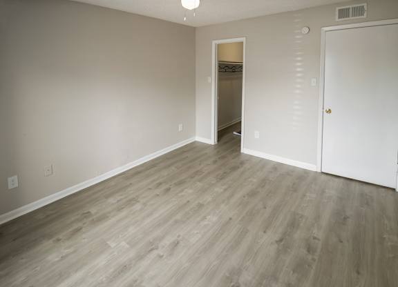 a spacious bedroom with an illuminated ceiling fan