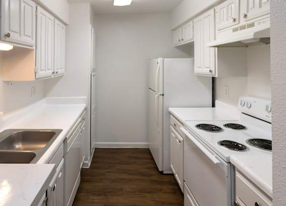 a kitchen with white appliances, white cabinets, and wood-style flooring