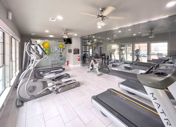 a gym with treadmills and other exercise equipment at Crosby at Westchase apartments in houston, tx
