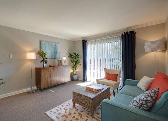 a spacious living room with modern features, model furnishings, and a sliding glass door