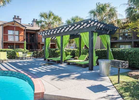 a pergola with loungers, and curtains, and a poolside grill at Hudson at Westchase