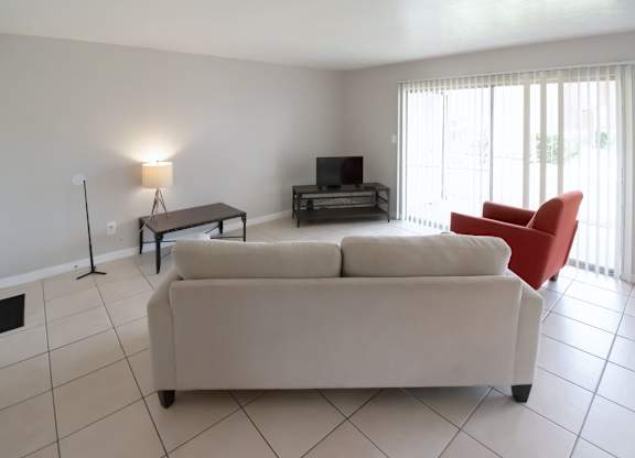 a tiled living room with sliding glass doors and model furnishings