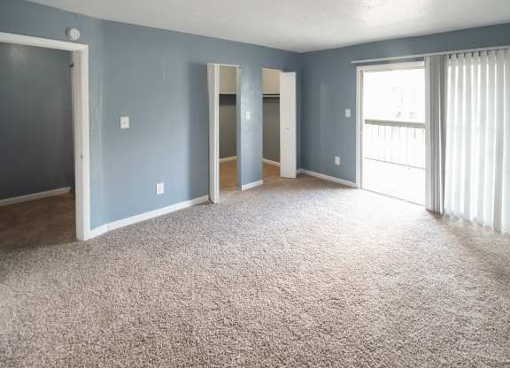 A spacious bedroom with large closets, sliding glass doors to a deck and carpet at Winford Place