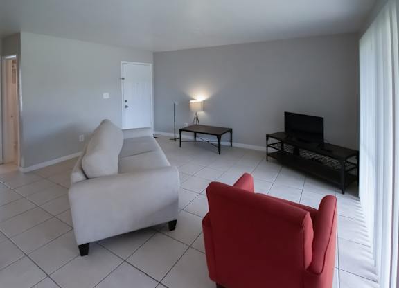 a large living room with a tiled floor, ample natural light, and model furnishings