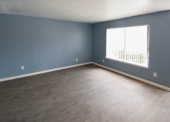 a large room with a big window and wood-style flooring in a Winford Place home