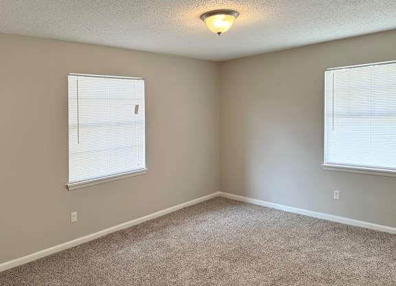 an empty bedroom with two windows and a carpeted floor at Spring Lake Cove Apartments, Birmingham, AL 35215
