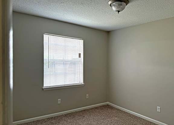an empty bedroom with a window and a ceiling fan at Spring Lake Cove Apartments, Alabama