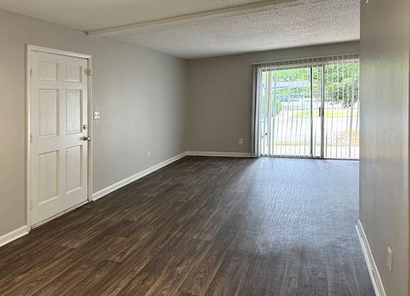 a spacious living room with a door and a sliding glass door to a private patio at Spring Lake Cove Apartments, Birmingham Alabama
