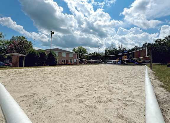 a sand volleyball court with a building in the background at Ascot Place Apartments, Alabama