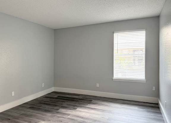 an empty room with wood floors and a window at Ascot Place Apartments, Birmingham