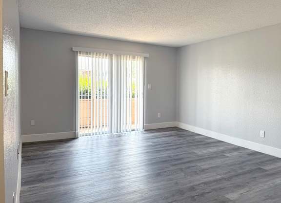 an empty living room with wood floors and a sliding glass door at Ascot Place Apartments, Birmingham, AL 