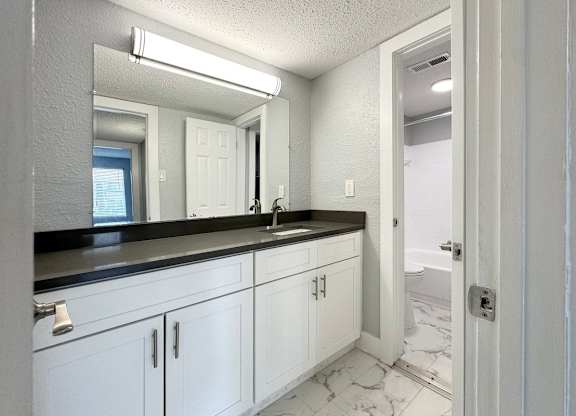 a bathroom with white cabinets and a sink and a mirror at Ascot Place Apartments, Birmingham, AL 35235 