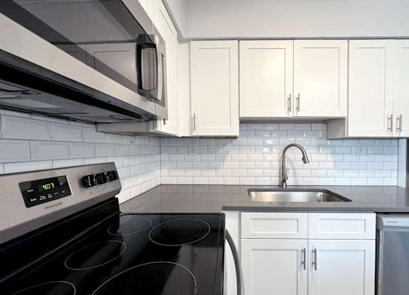 a white kitchen with black appliances and white cabinets at Ascot Place Apartments, Birmingham, AL 35235
