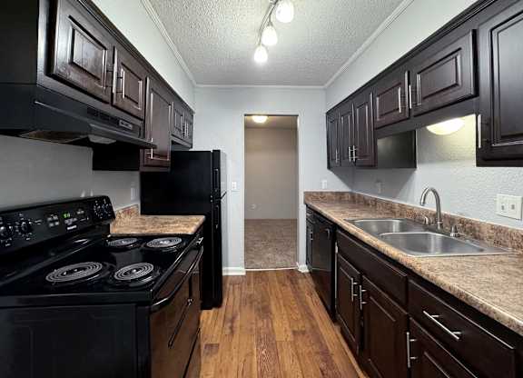 a kitchen with black appliances and dark wood cabinets at Ascot Place Apartments, Birmingham, AL 35235