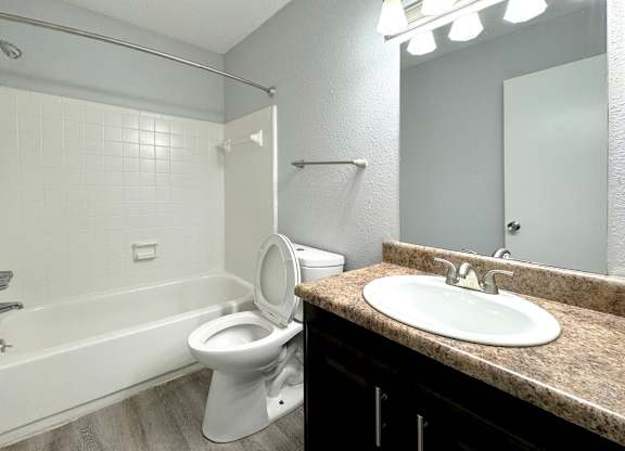 a bathroom with a toilet and a sink and a bath tub at Ascot Place Apartments, Alabama