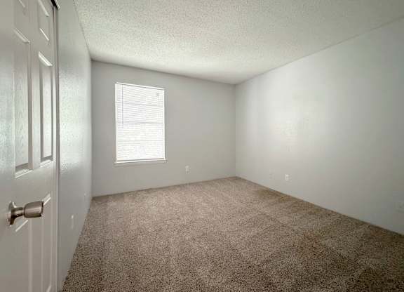 an empty room with carpet and a window at Ascot Place Apartments, Birmingham, AL