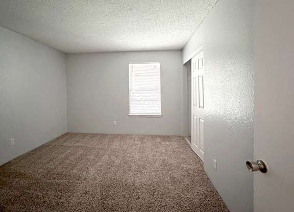 an empty room with carpet and a window at Ascot Place Apartments, Birmingham Alabama