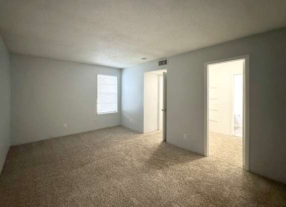 an empty living room with carpet and a door to a bedroom at Ascot Place Apartments, Birmingham, AL