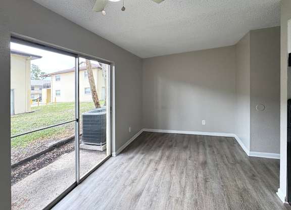 A room with a sliding glass door leading to a backyard.