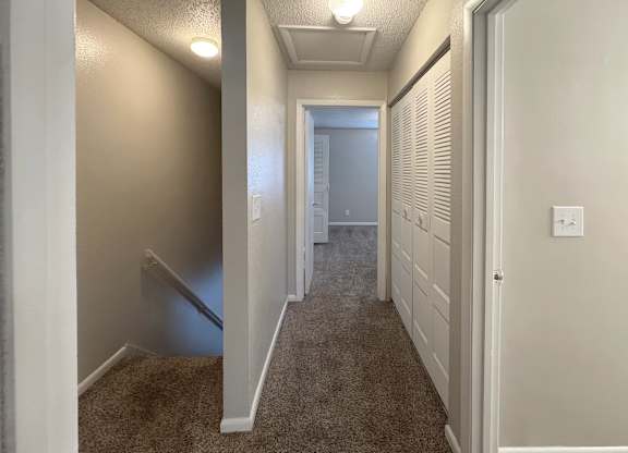 A hallway with a carpeted floor and white walls.