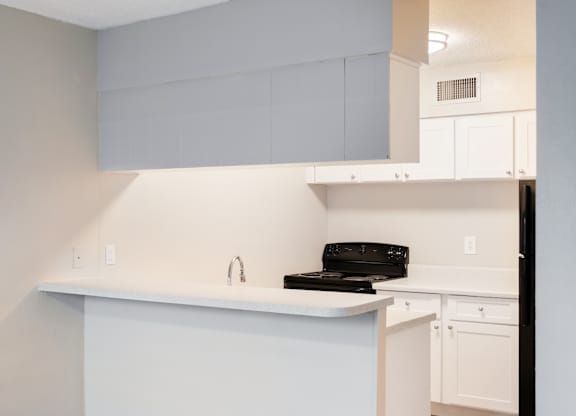 a kitchen with white cabinets and a black stove
