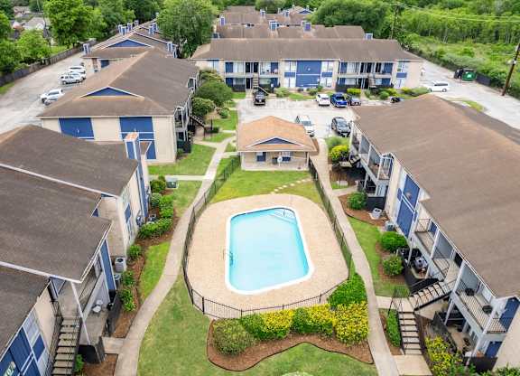 A swimming pool is surrounded by a fence and houses. at Pine Creek Apartments, Houston, 77013
