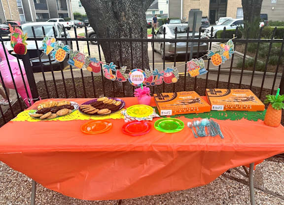 A table with an orange tablecloth is set up for an event.