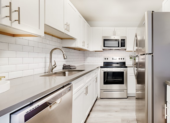 a modern kitchen with stainless steel appliances and white cabinets at Spring Lake Cove Apartments, Birmingham Alabama