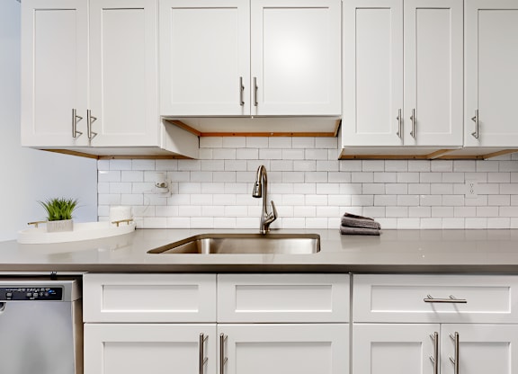 kitchen with tile backsplash, white cabinets, and stainless steel sink at Spring Lake Cove Apartments, Birmingham, 35215 