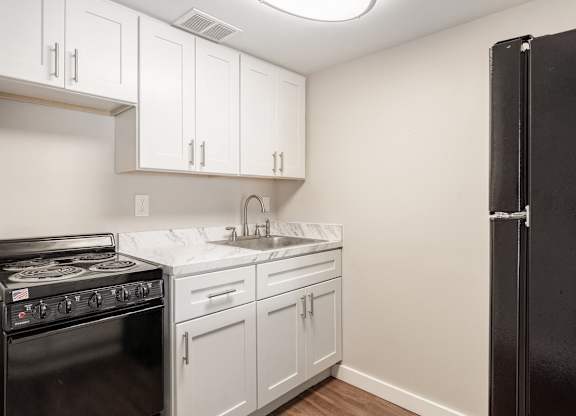 a Waterview Crossing Apartment kitchen with white cabinets and a black appliances