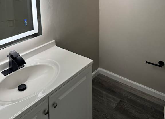 a renovated bathroom with smart mirror, white sink and toilet, and black fixtures
