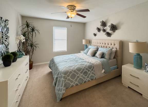 a bedroom with plush carpeting, an illuminated ceiling fan, a window, and model furniture
