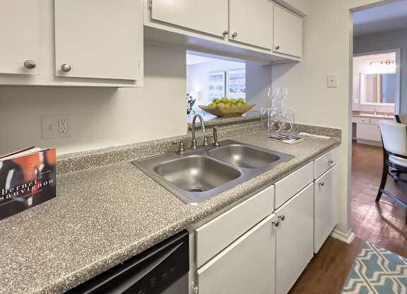 a kitchen with a double stainless steel sink, granite-inspired counter top, and white cabinets