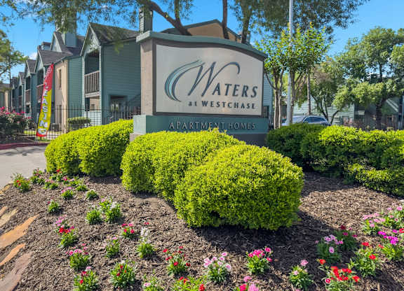 The Waters at Westchase Monument sign surrounded by flowers and lush bushes