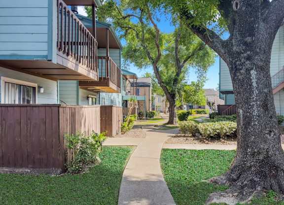 a lush courtyard with neat sidewalks between residential buildings at Waters at Westchase Apartments