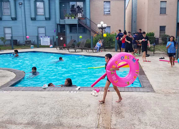 A person is holding a pink inflatable ring at a pool party
