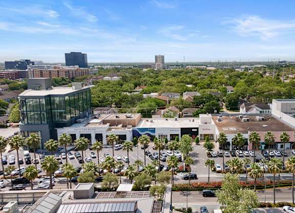 A cityscape with a large building in the center and a parking lot in the foreground.