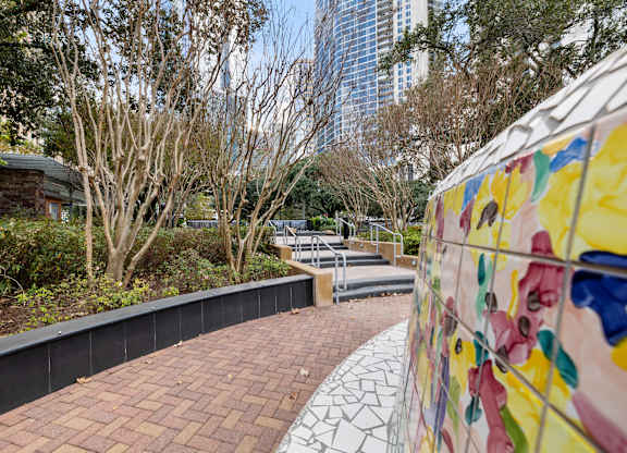 A wall with a mural of flowers is on the right side of a brick path.