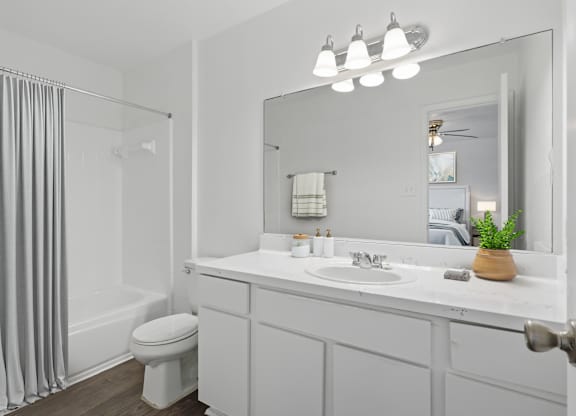 A white bathroom with a toilet, sink, and mirror.